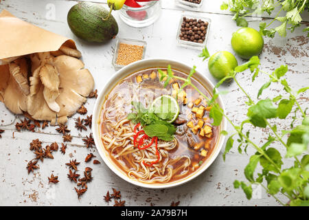 Zuppa PHO con la menta, coriandolo, tofu, caramellato funghi orecchioni, calce, riso tagliatelle e peperoncino. Oriental zuppa vietnamita Foto Stock