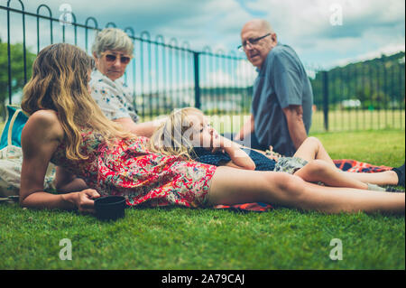 Un autentico colpo di un bimbo rilassante con sua madre e i nonni nel parco Foto Stock