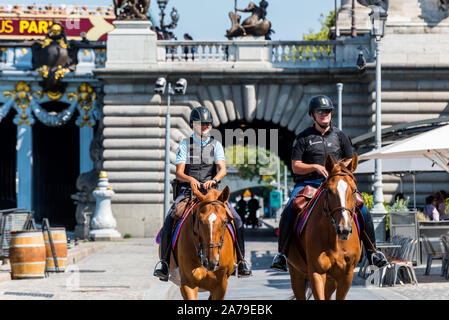 Montati due funzionari di polizia su cavalli pattugliano attraverso la passerella del fiume Senna nel centro di Parigi, Francia. Foto Stock