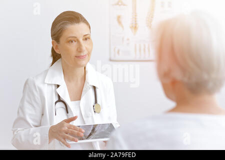 Medico donna con un immagine mra angiogramma o discutere con un paziente senior il rischio di soffrire di una corsa apoplectic, spazio di copia Foto Stock