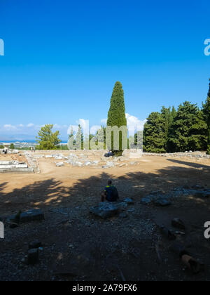 Seduto tourist ammirando la vista e le rovine del tempio di guarigione Asclepeion Foto Stock