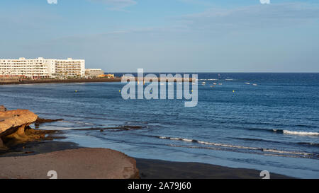 El Medano, Tenerife, Isole Canarie, Spagna - 27 Marzo 2019: vista della spiaggia vulcanica verso il resort hotel, ristoranti e terrazze Foto Stock