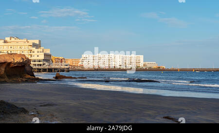 El Medano, Tenerife, Isole Canarie, Spagna - 27 Marzo 2019: vista della spiaggia vulcanica verso il resort hotel, ristoranti e terrazze Foto Stock