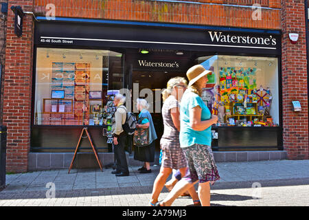 Gli amanti dello shopping passando dalla shopfront del famoso libro rivenditore Waterstone's, nel centro di Dorchester su una soleggiata giornata estiva. Foto Stock