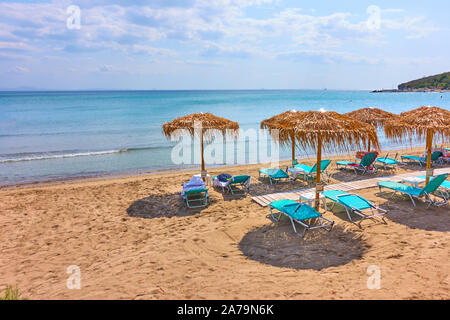 Spiaggia con ombrelloni di paglia dal mare sulla soleggiata giornata estiva, Agia Marina, Aegina Island, Grecia - Greco Resort Foto Stock