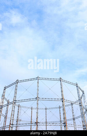 Arrugginimento gasometro contro un cielo blu con nuvole Foto Stock