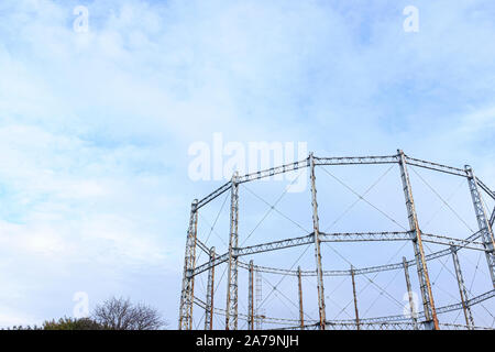 Arrugginimento gasometro contro un cielo blu con nuvole Foto Stock