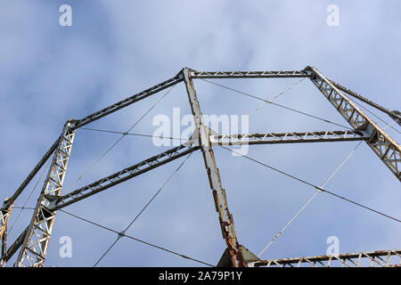 Arrugginimento gasometro contro un cielo blu con nuvole Foto Stock