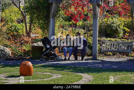 Boothbay, ME / STATI UNITI D'America - 19 Ottobre 2019: nuova coppia trascorrere del tempo insieme con il bambino su altalena in Costa del Maine Giardini botanici Foto Stock