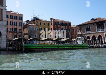 Massiccio consegna verde barcone sul Canal Grande Venezia la consegna al coperto bancarelle di frutta e verdura e il famoso mercato del pesce Foto Stock