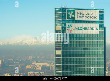 Milano Italia: Regione Lombardia headquarters building con le alpi italiane e il Monte Rosa in background. Città di Milano coperto dallo smog. Foto Stock