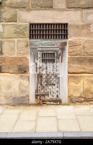 Una vecchia prigione porta cellulare impostato in un muro di pietra a Warwick Foto Stock