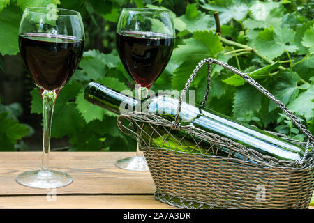 Vino rosso bicchieri con foglie di vite nel giardino Foto Stock