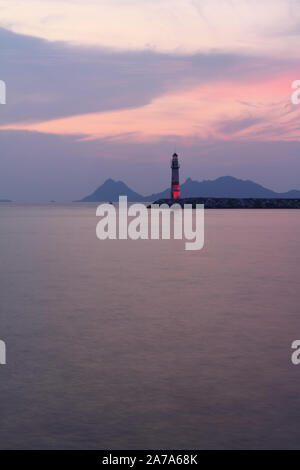 Seascape al tramonto. Faro sulla costa. Città balneare di Turgutreis e tramonti spettacolari Foto Stock