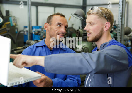 Due ingegneri maschio guardando il laptop in officina Foto Stock