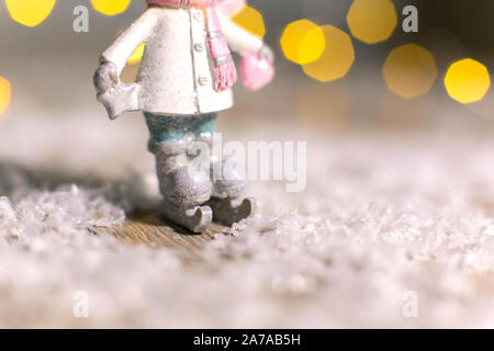Decorazione di Natale figurine a tema. Statuetta di un uomo sui pattini. Decorazione per albero di Natale. Decorazioni festive, calde luci bokeh di fondo Foto Stock