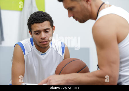 Coach di pallacanestro e il giocatore guardando la pianificazione Foto Stock