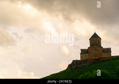 Gergeti Trinity Church noto anche come Tsminda Sameba sullo sfondo di un crinale e nuvole, Stepantsminda, Kazbegi, Georgia. Foto Stock