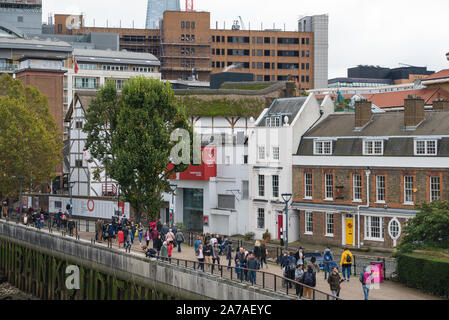 La gente camminare passato il Globe Theatre di Shakespeare sul Tamigi South Bank di Londra, England, Regno Unito Foto Stock