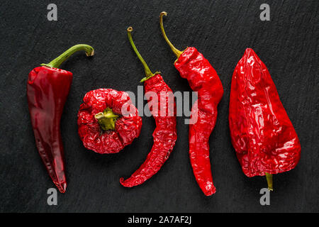 Red Banane essiccate peperoni in un grigio scuro ardesia Foto Stock