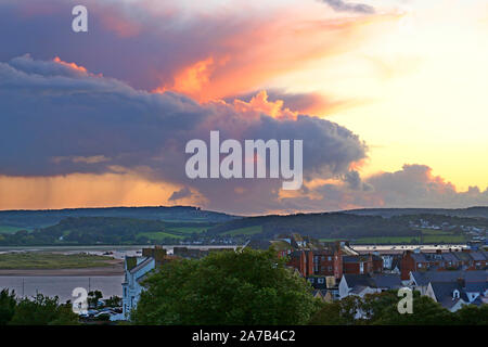 Cumulonimbus nuvole formando sul fiume Exe estuary approssimarsi al tramonto. Un mantello di pioggia che cade sulle lontane colline. Una luce dorata all'interno del cloud Foto Stock