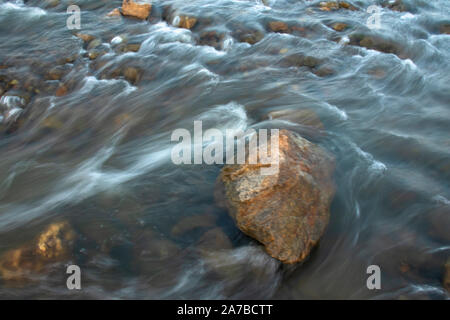 Gettare acqua di un fiume con il riflesso del cielo blu prese con una lenta velocità di otturatore. Foto Stock