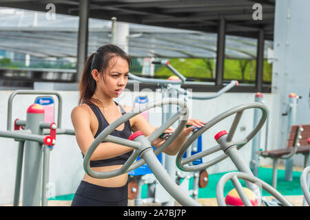 Uno conciate asian giovane donna con il nero marrone capelli lunghi in nero abbigliamento sportivo attivo esercizio di allenamento all'aperto Foto Stock