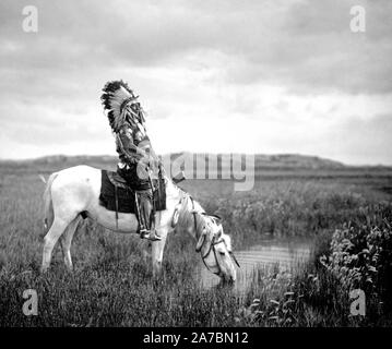 Edward S. Curtis nativi indiani americani - Rosso Hawk, un guerriero Oglala, seduto su un cavallo che è di bere da un piccolo stagno nel Badlands ca. 1905 Foto Stock