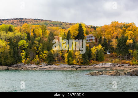 Casa nella foresta sul lago in Canada, in autunno, bellissimi colori degli alberi, la riflessione sull'acqua Foto Stock