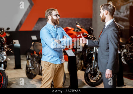 Consulente di vendita con un cliente la scelta di moto sportive di acquistare presso lo showroom Foto Stock