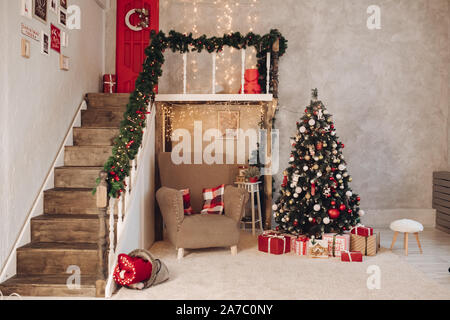 Stock foto della festa di Natale decorato interno. Garland, albero di Natale, regali avvolti sul pavimento. Atmosfera accogliente. Foto Stock