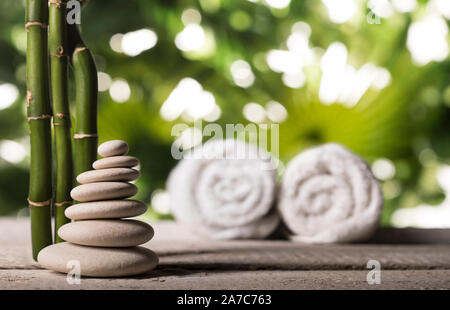 Grean foglie di bambù su bianco zen piramide di pietre su foglie tropicali sfondo Foto Stock