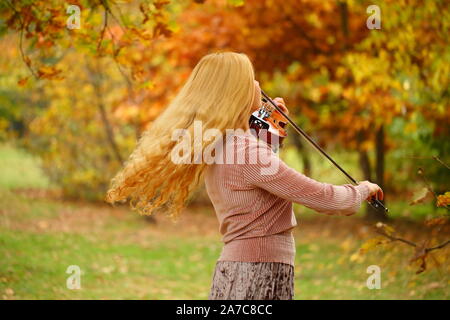 Ragazza suona il violino in autunno park Foto Stock