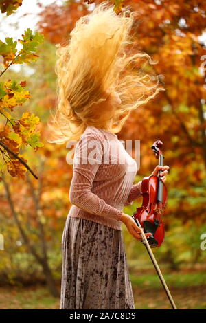 Ragazza suona il violino in autunno park Foto Stock