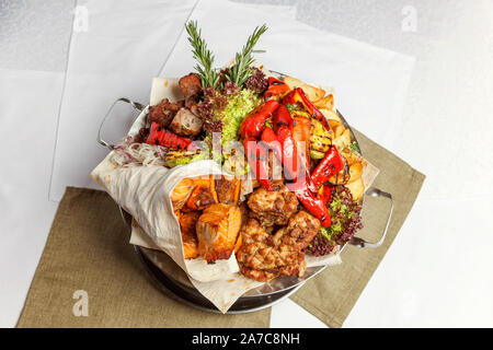 Grigliata mista di carne, verdure fritte e salmone alla griglia con i filetti di pesce decorazione nel piatto caldo. Un assortimento di deliziosi kebab grigliato servito con le erbe sul piatto da portata. Il menu del ristorante piastra Foto Stock