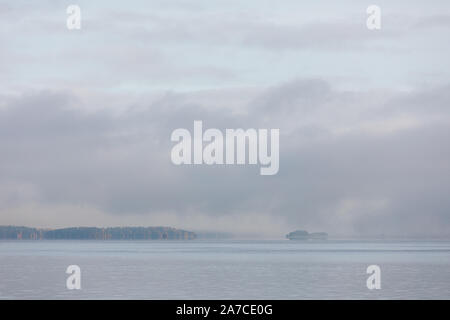 Il lago di scape e nebbioso sponda opposta foresta all'alba Foto Stock