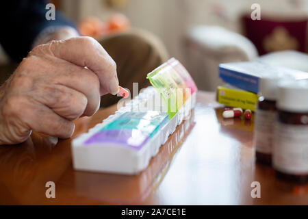 Close up uomo Senior di organizzazione di un farmaco in pillola Dispenser Foto Stock