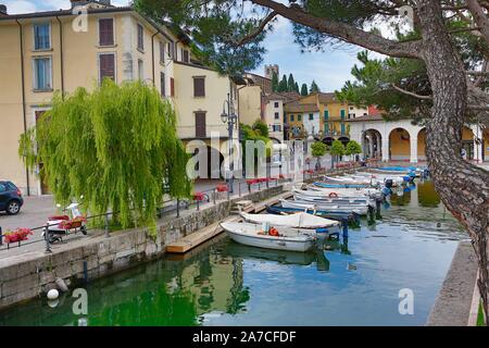 Der kleine Hafen in der Altstadt von Desenzano del Garda kann mit Booten durch eine kleine, geschwungene Brücke vom Gardassee aus berreicht werde. Sch Foto Stock