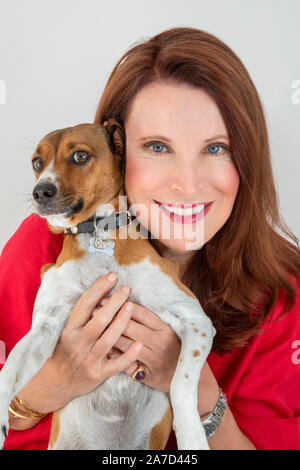 Donna sorridente mentre tiene il suo cane Foto Stock