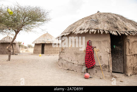 Arusha, Tanzania, 8 Settembre 2019: Maasai kid con un calcio al di fuori la sua casa Foto Stock