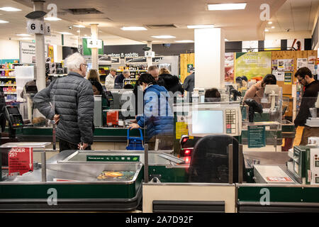 Morrisons supermercato area check-out, persone fodera fino alla cassa fino a pagare e il pack il loro shopping alimentare, London, England, Regno Unito Foto Stock