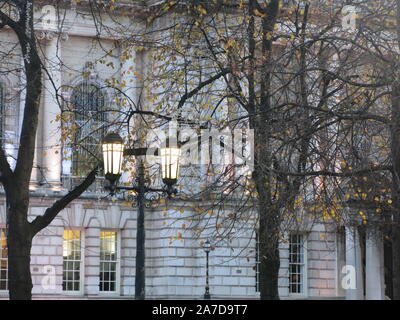La facciata del Municipio di Belfast con inverno alberi in primo piano e lanterne accese al tramonto. Foto Stock
