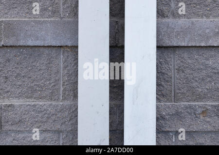 Grigio pietra muro di mattoni con due bianchi lunghe strisce al centro della foto. Foto Stock