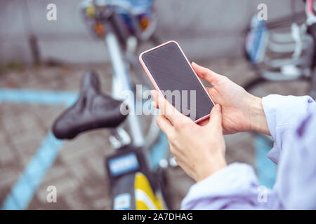 Donna con una bicicletta e un telefono cellulare Foto Stock