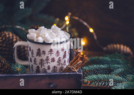 Abete colorato tazza ceramica con un caffè o una cioccolata calda con marshmallows sul luminoso sullo sfondo di legno con scintillante garland Foto Stock