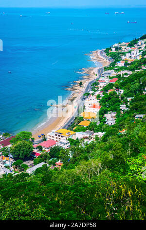 Famosa città costiera in Vietnam Vung Tau, shore vista. Case sul pendio di una collina in una densa vegetazione Foto Stock