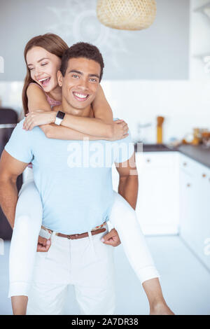 Affascinante giovane donna è abbracciando uomo sorridente Foto Stock
