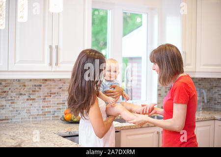 Il concetto di maternità, nanny, l'infanzia e la fanciullezza. Piscina shot in cucina. Due donne e un bambino in braccio, guardando verso la fotocamera e s Foto Stock