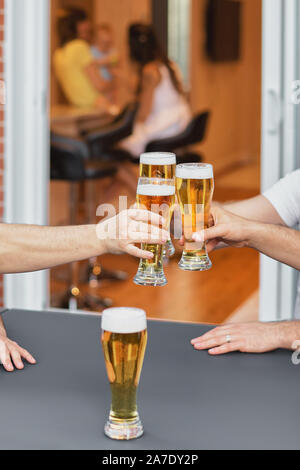 Immagine ritagliata mani di un gruppo di voiced bicchieri di birra, feste e celebrazioni. bicchieri da birra in casa sulla terrazza della casa, la famiglia di un Foto Stock