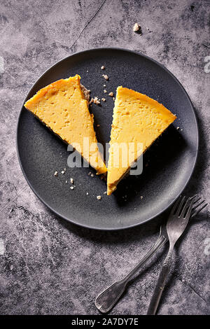 Due fette di zucca cheesecake servita su una piastra nera Foto Stock